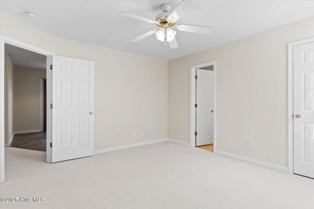 unfurnished bedroom with light carpet, a textured ceiling, a ceiling fan, and baseboards