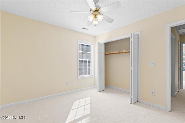 unfurnished bedroom with a textured ceiling, light carpet, visible vents, baseboards, and a closet