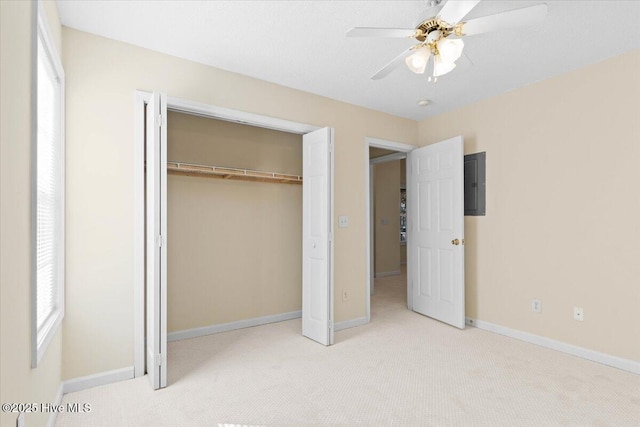 unfurnished bedroom with a closet, light carpet, ceiling fan, electric panel, and baseboards