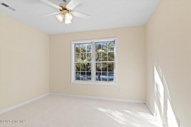 empty room with light carpet, visible vents, baseboards, and a ceiling fan