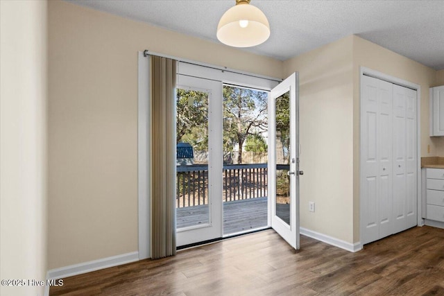 entryway with a textured ceiling, wood finished floors, and baseboards