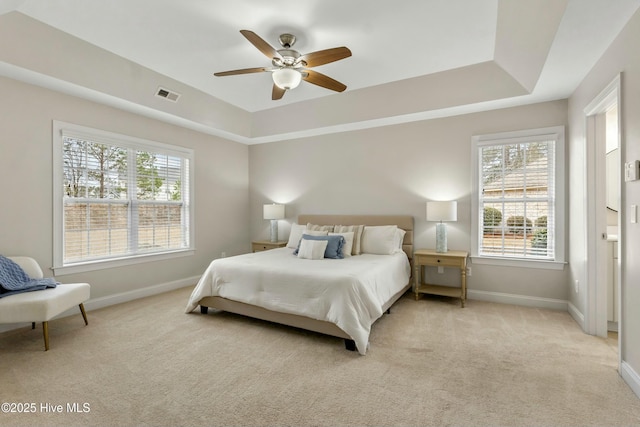 bedroom featuring light carpet, baseboards, and a raised ceiling