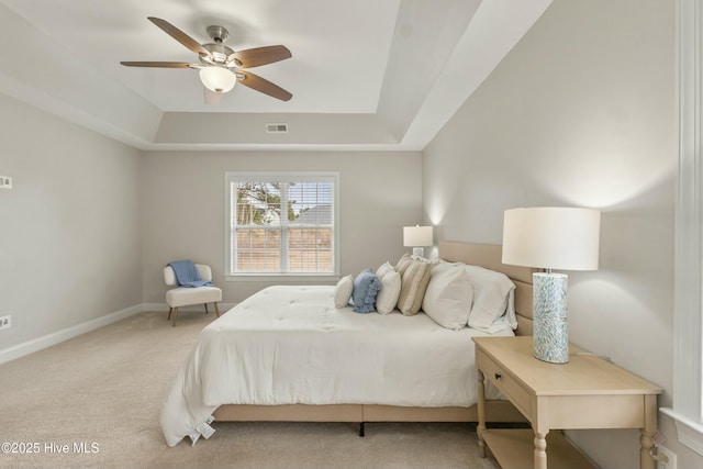 bedroom with light carpet, baseboards, visible vents, a ceiling fan, and a tray ceiling