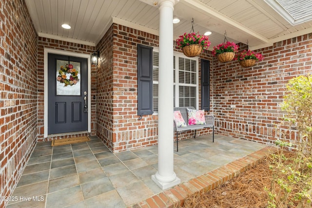 property entrance featuring brick siding and a porch