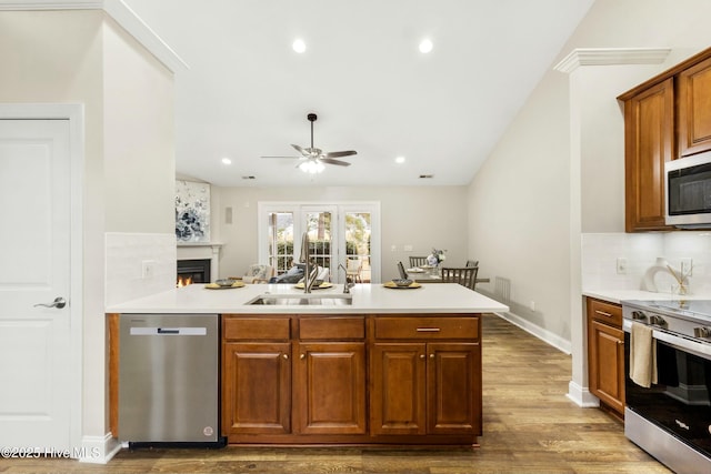 kitchen with stainless steel appliances, dark wood-style flooring, light countertops, backsplash, and brown cabinetry