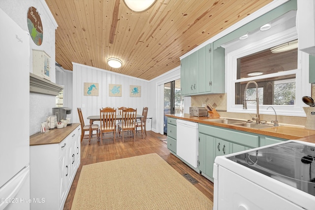 kitchen featuring white appliances, butcher block countertops, dark wood-style flooring, green cabinets, and a sink