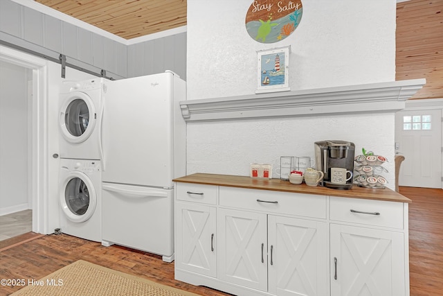 laundry room featuring wooden ceiling, light wood-style flooring, laundry area, stacked washer / dryer, and ornamental molding