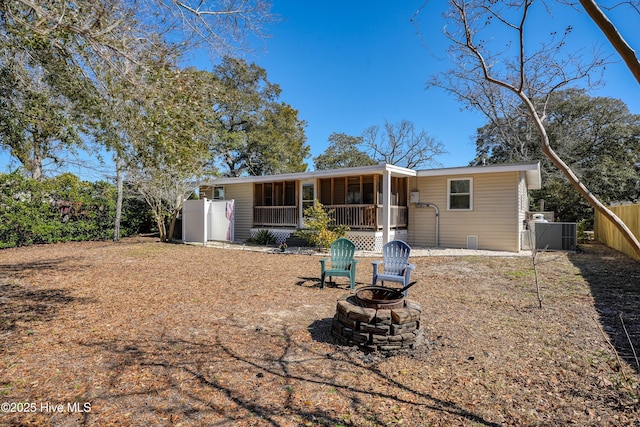 rear view of house with a fire pit, central AC, and fence