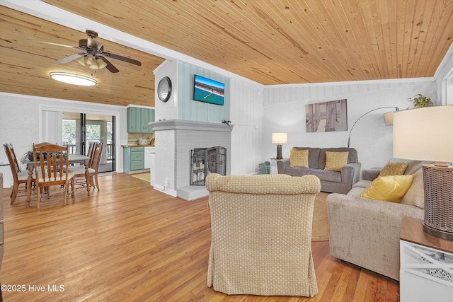 living area featuring lofted ceiling, wooden ceiling, light wood-style flooring, and a brick fireplace