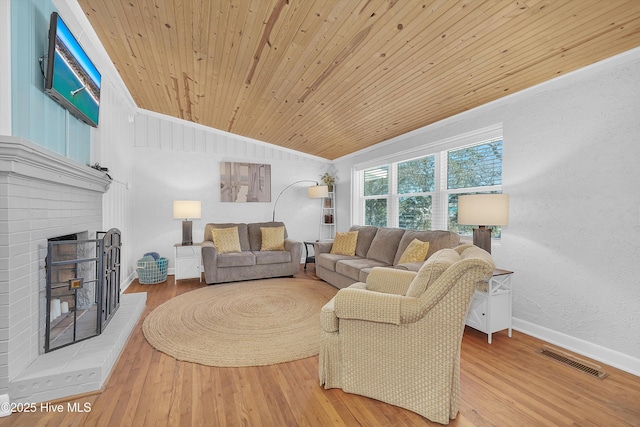 living area with a fireplace, visible vents, vaulted ceiling, wood finished floors, and wooden ceiling