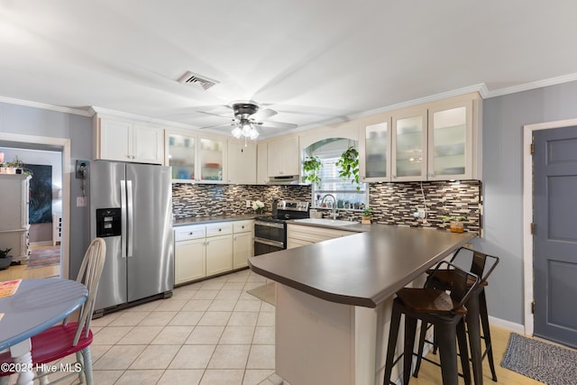 kitchen featuring a peninsula, appliances with stainless steel finishes, a sink, and crown molding