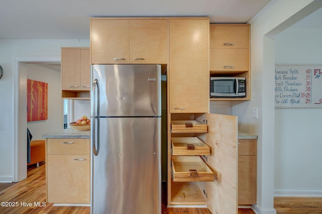 kitchen with stainless steel appliances, light wood-type flooring, light countertops, and light brown cabinetry