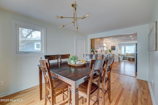 dining area featuring light wood-type flooring, an inviting chandelier, and baseboards