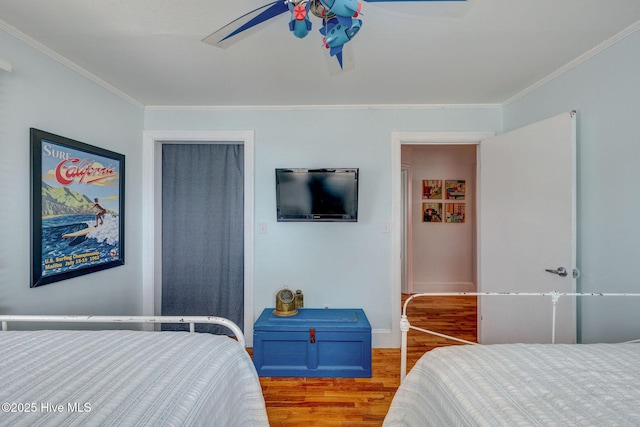 bedroom featuring baseboards, wood finished floors, a ceiling fan, and crown molding