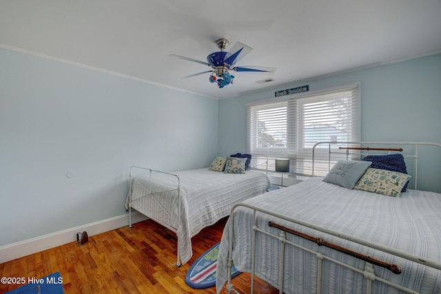 bedroom with visible vents, ornamental molding, a ceiling fan, wood finished floors, and baseboards