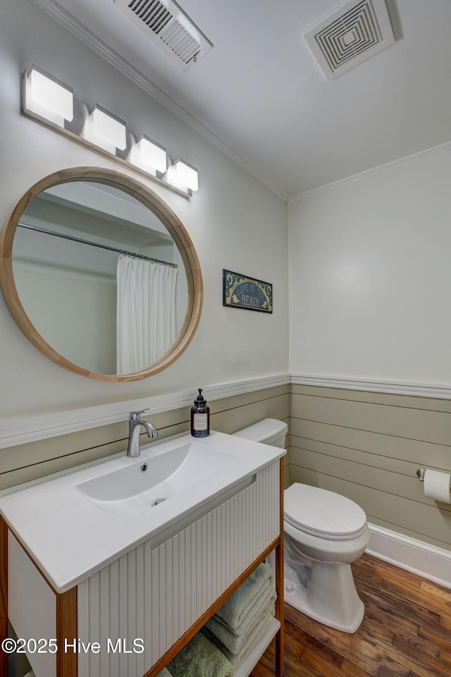 full bath with a wainscoted wall, toilet, wood finished floors, and visible vents