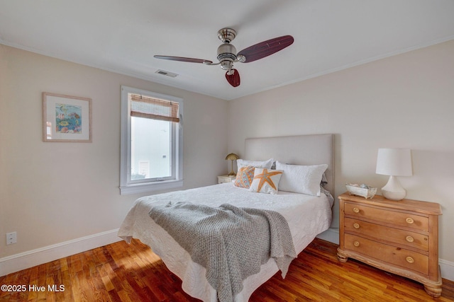 bedroom with ceiling fan, wood finished floors, visible vents, and baseboards