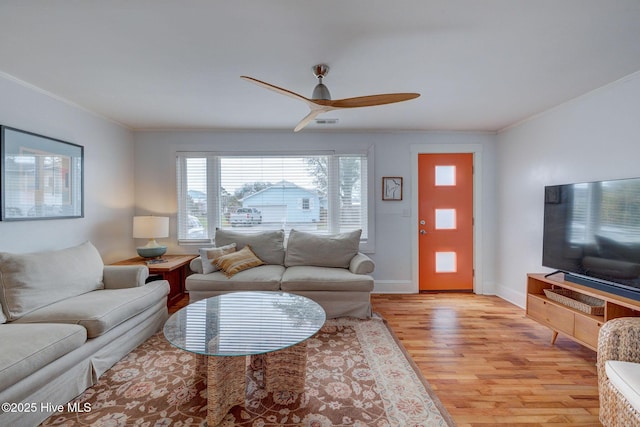 living area with ornamental molding, light wood finished floors, visible vents, and baseboards