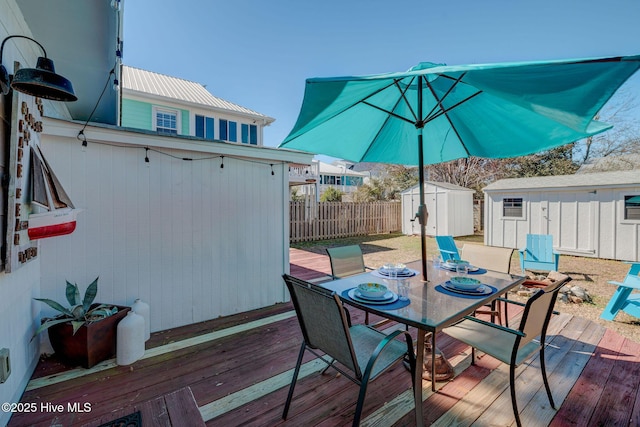 deck with a storage shed, outdoor dining area, an outdoor structure, and fence