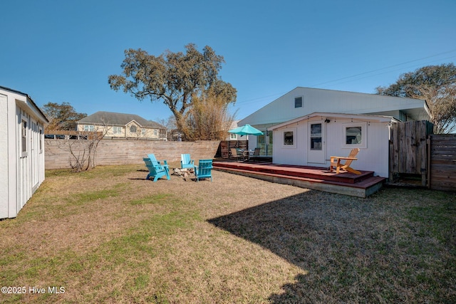 view of yard with an outbuilding, a fenced backyard, and a deck