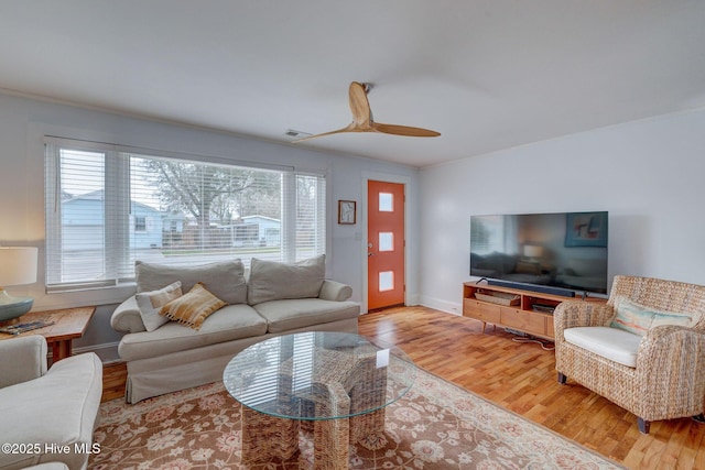 living area with visible vents, a ceiling fan, ornamental molding, wood finished floors, and baseboards