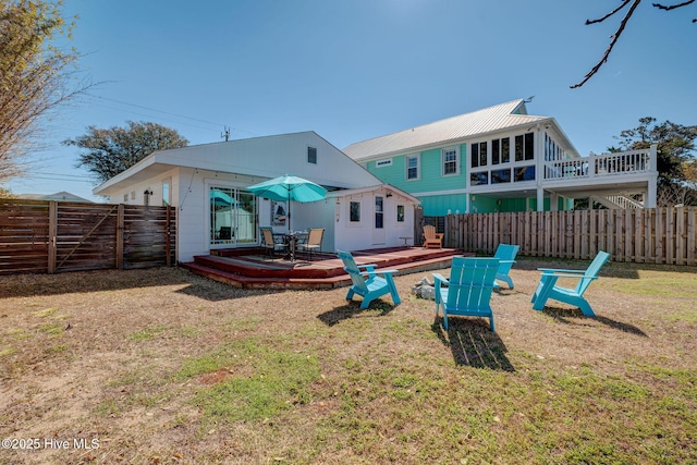 back of property with a deck, a lawn, and a fenced backyard