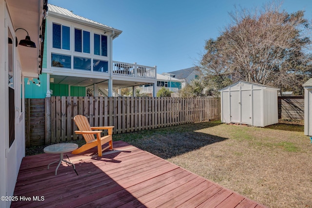 deck featuring an outbuilding, a yard, a storage unit, and a fenced backyard