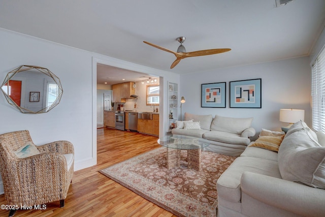 living room featuring ceiling fan, light wood-style flooring, and baseboards