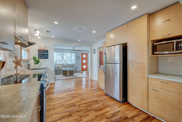 kitchen with light wood-style floors, open floor plan, light countertops, appliances with stainless steel finishes, and light brown cabinetry