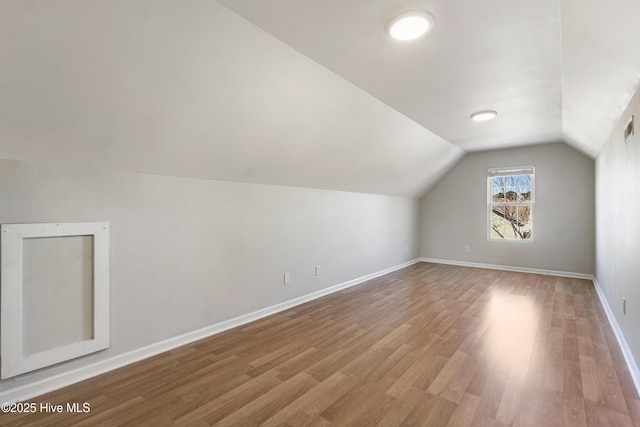 bonus room with light wood-type flooring, visible vents, lofted ceiling, and baseboards