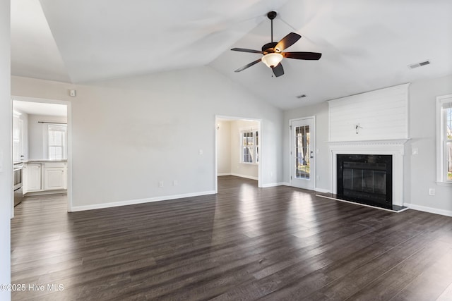 unfurnished living room featuring lofted ceiling, dark wood-type flooring, visible vents, baseboards, and a glass covered fireplace