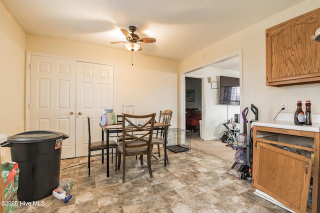 dining space with ceiling fan, baseboards, and a textured ceiling