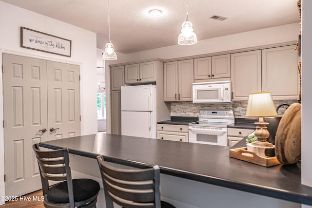 kitchen with white appliances, dark countertops, tasteful backsplash, hanging light fixtures, and a textured ceiling