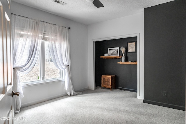 unfurnished bedroom with carpet, a textured ceiling, baseboards, and a ceiling fan