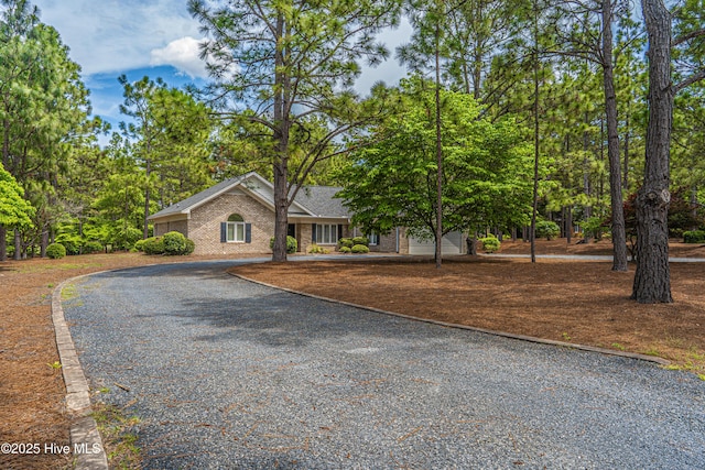 view of front of house featuring curved driveway and brick siding