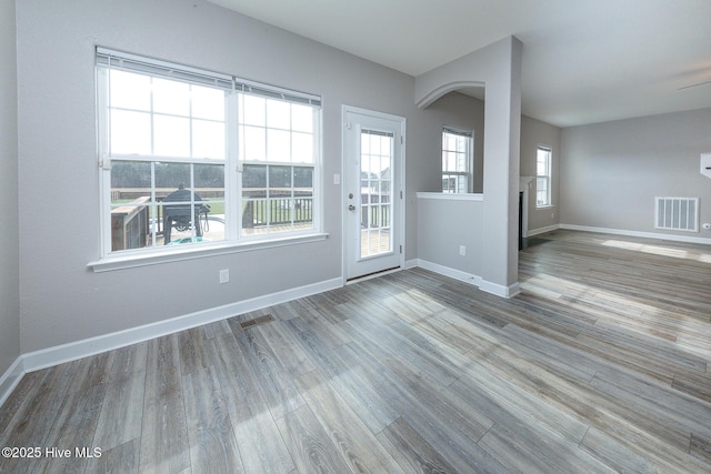 spare room featuring baseboards, visible vents, vaulted ceiling, and wood finished floors