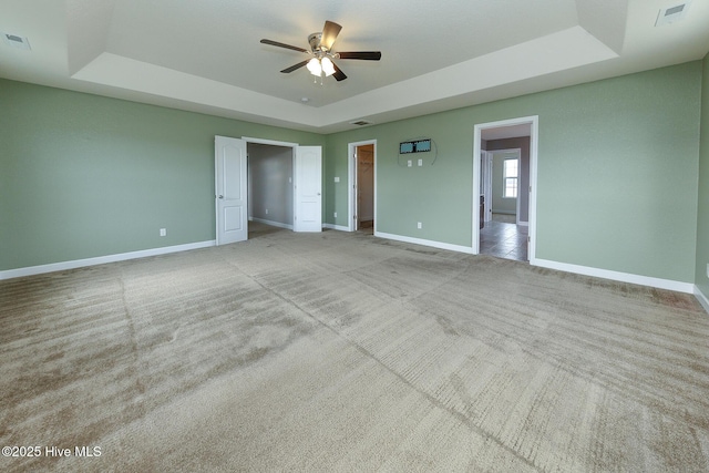 unfurnished bedroom featuring a raised ceiling, carpet flooring, and baseboards