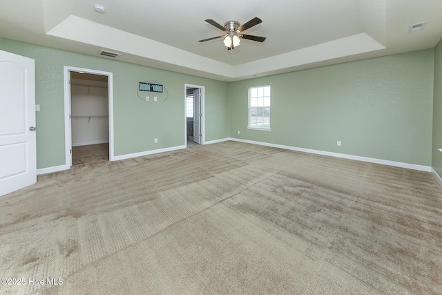 spare room featuring baseboards, visible vents, a tray ceiling, and carpet flooring