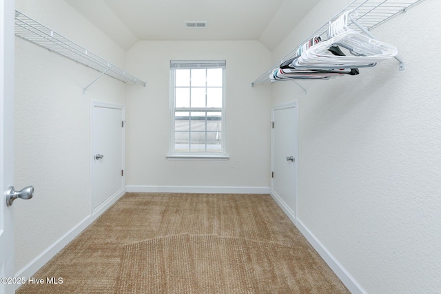 walk in closet featuring lofted ceiling, carpet, and visible vents