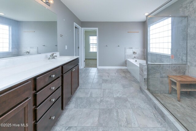 bathroom featuring a garden tub, baseboards, and vanity