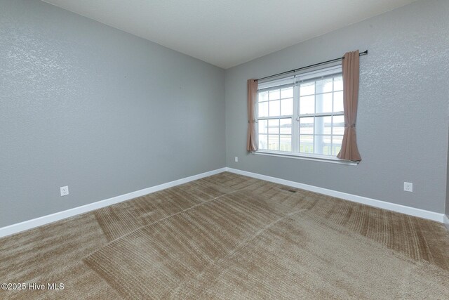 empty room featuring carpet and baseboards