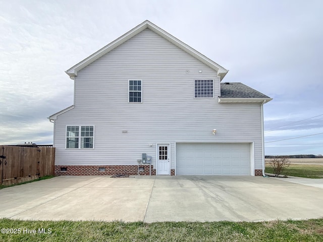 back of property featuring a garage, fence, concrete driveway, crawl space, and roof with shingles