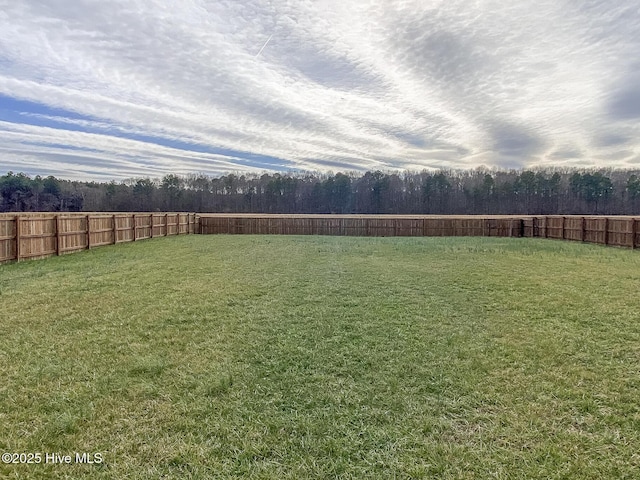 view of yard featuring a wooded view and fence