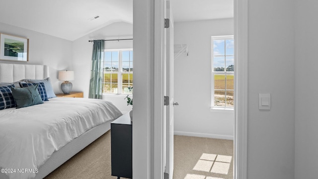 bedroom featuring multiple windows, lofted ceiling, and light colored carpet