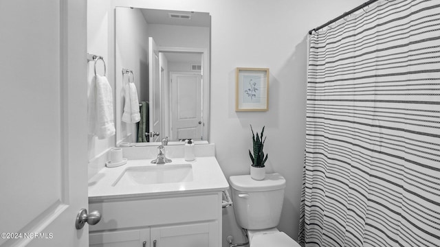 bathroom with curtained shower, vanity, and toilet