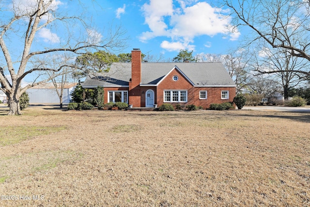 view of front of house featuring brick siding, a chimney, and a front lawn