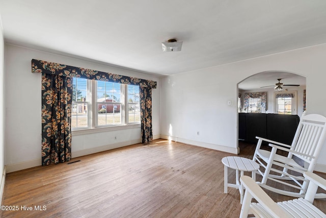 sitting room with a wealth of natural light, arched walkways, visible vents, and wood finished floors