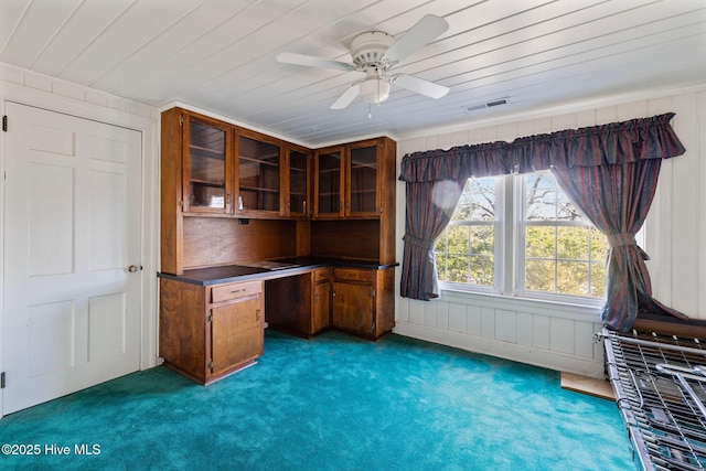 unfurnished office with visible vents, wood ceiling, ceiling fan, dark carpet, and built in desk