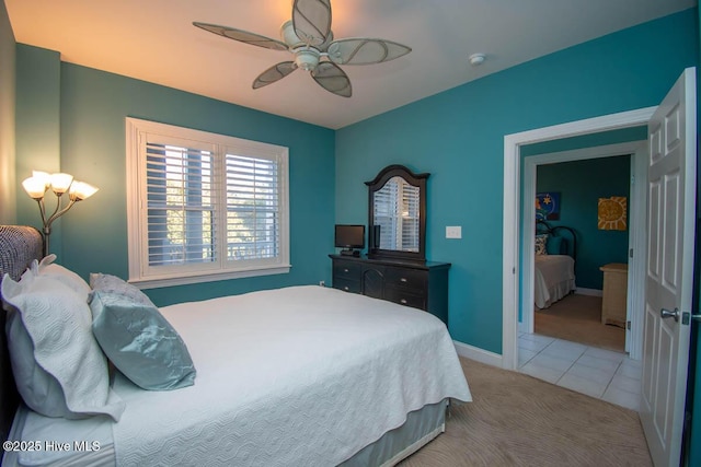 bedroom with light tile patterned floors, baseboards, a ceiling fan, and light colored carpet