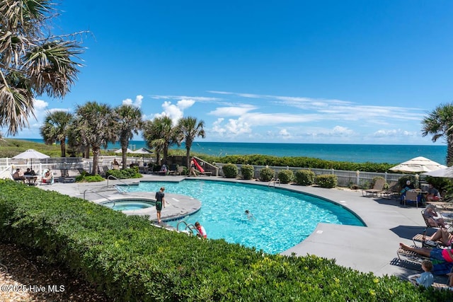 community pool with a patio area, a community hot tub, a water view, and fence